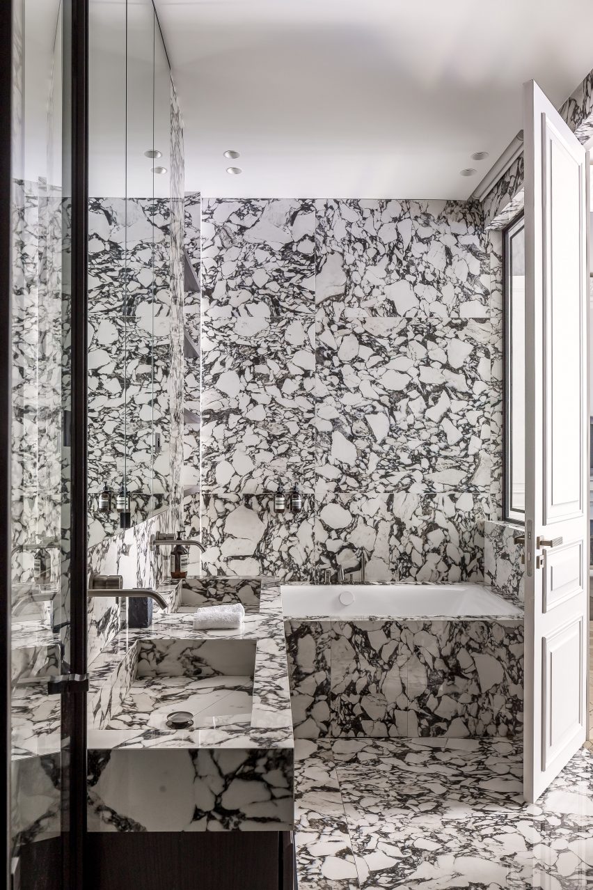 Bathroom with walls and floors lined entirely in dramatic black and white marble
