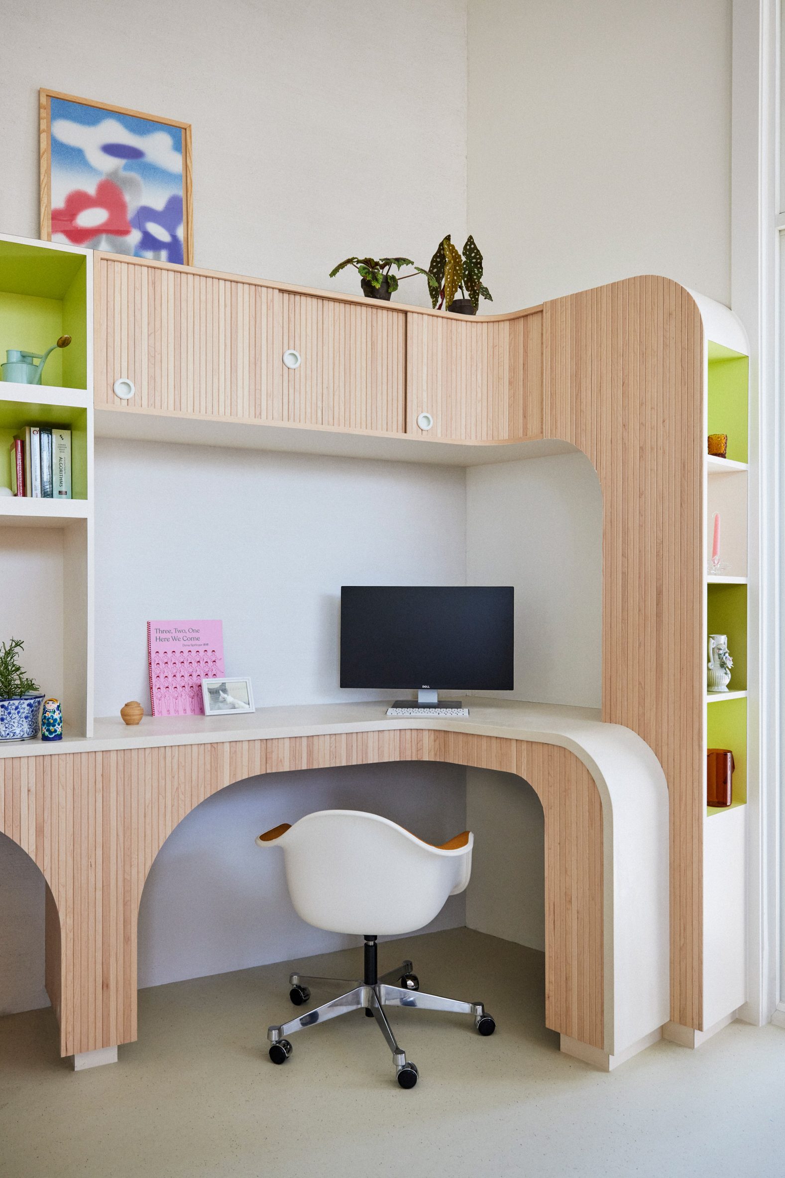 A work-from-home area where pale wood panels are contrasted by lime-green storage niches