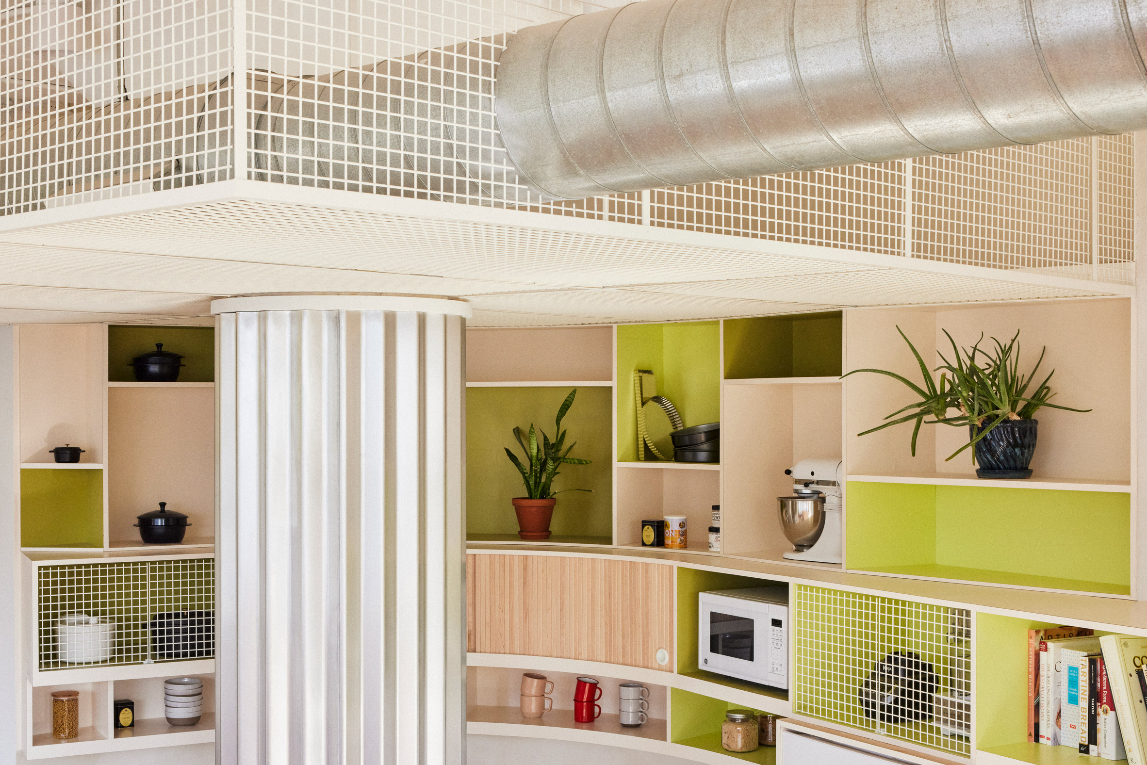Exposed ductwork and white powder-coated mesh boxes on the kitchen ceiling