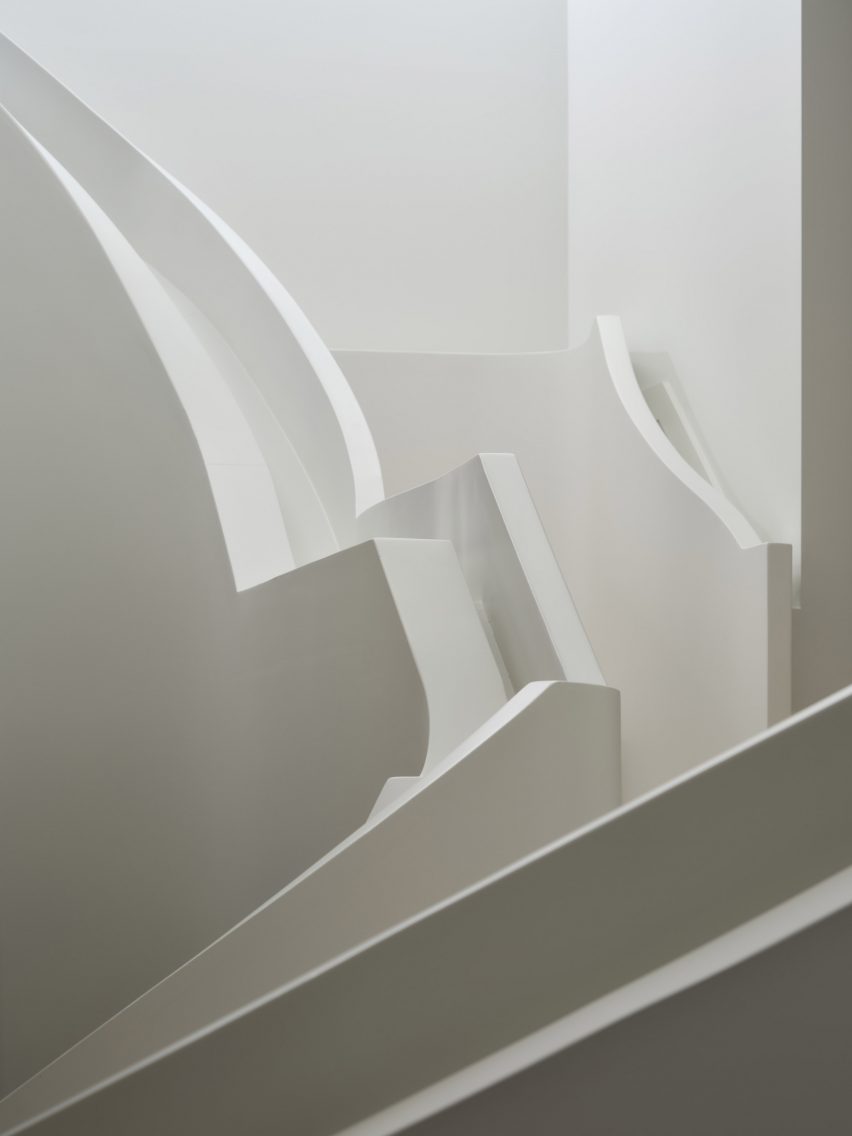 La scala scultorea presenta balaustre stratificate, profili a gradini e una forma curva