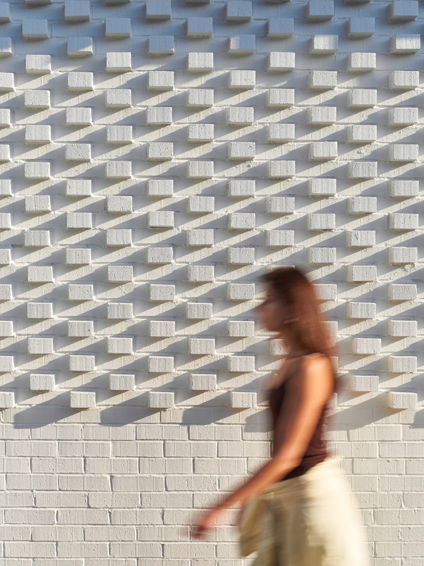 Woman walking by brick wall