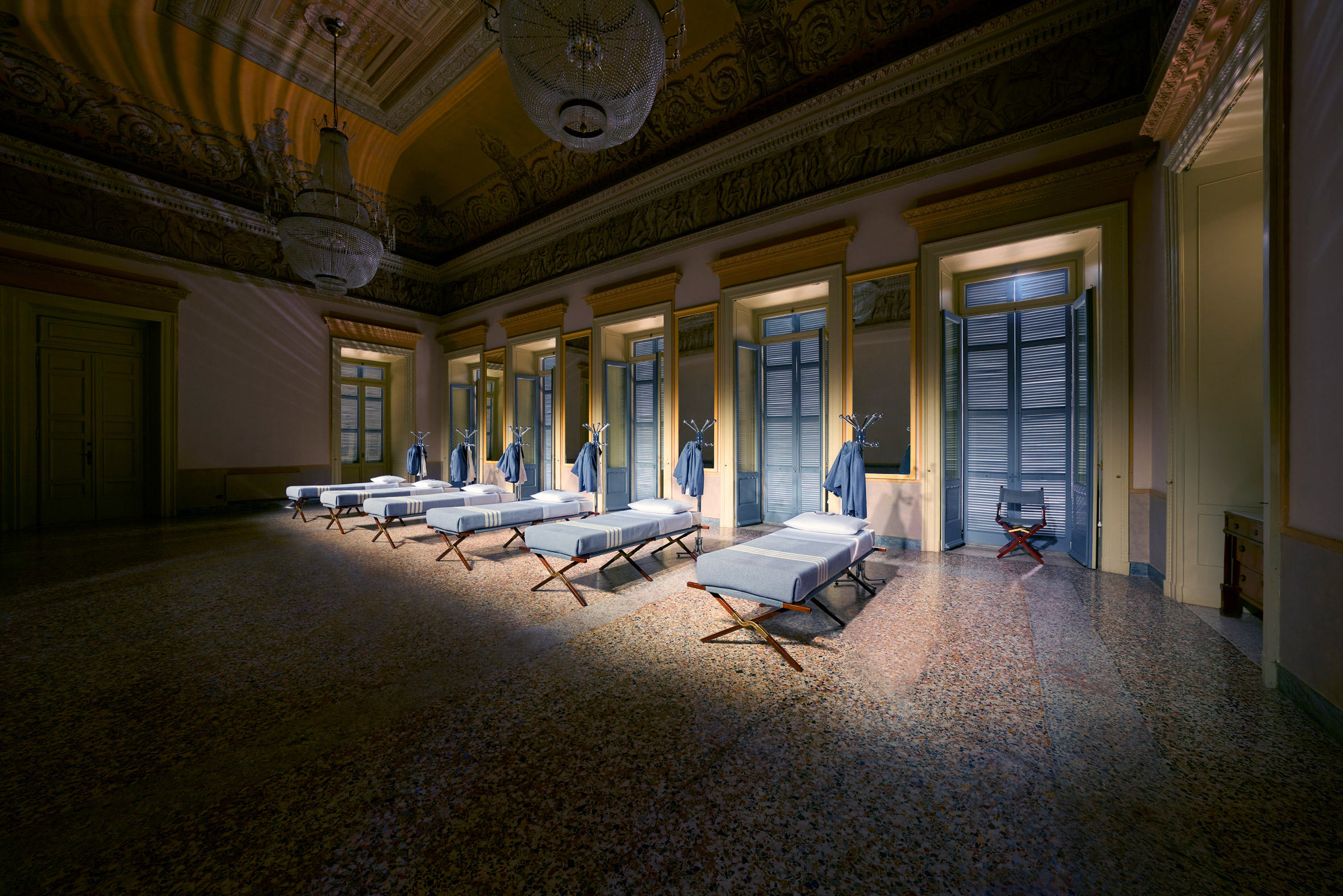 Six identical beds placed in a row inside a decorative salon