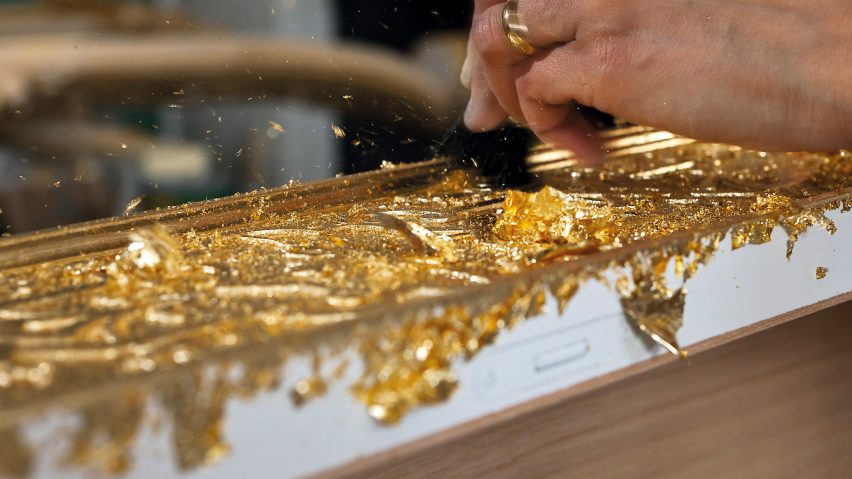 a hand working on the golden covering of a cabinet