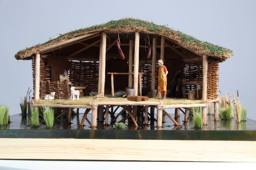 An architectural model displaying a woven hut on water.