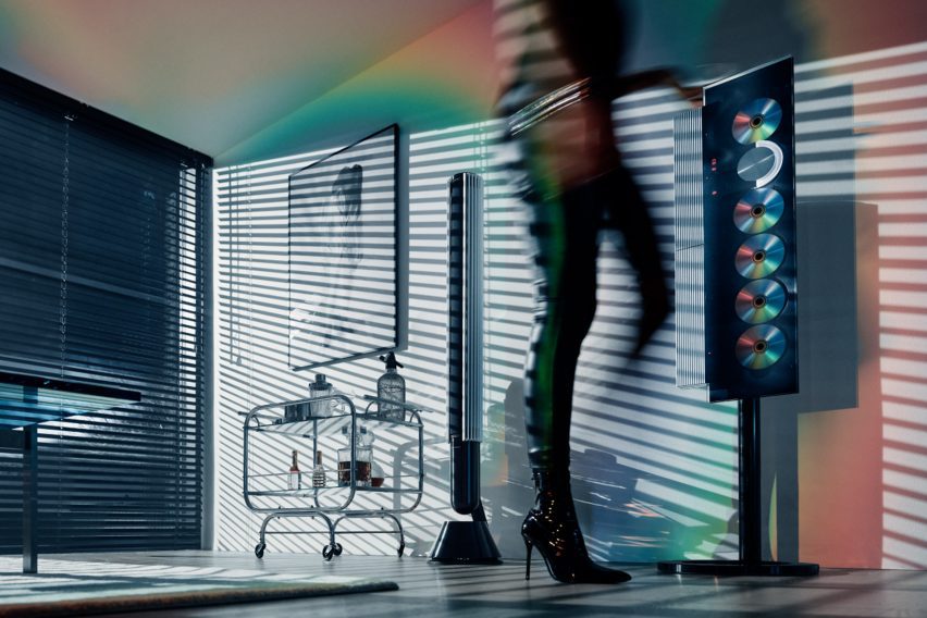 Lifestyle photo of a woman in tight black leather pants walking past the Beosystem 9000c six-CD player system by Bang & Olufsen