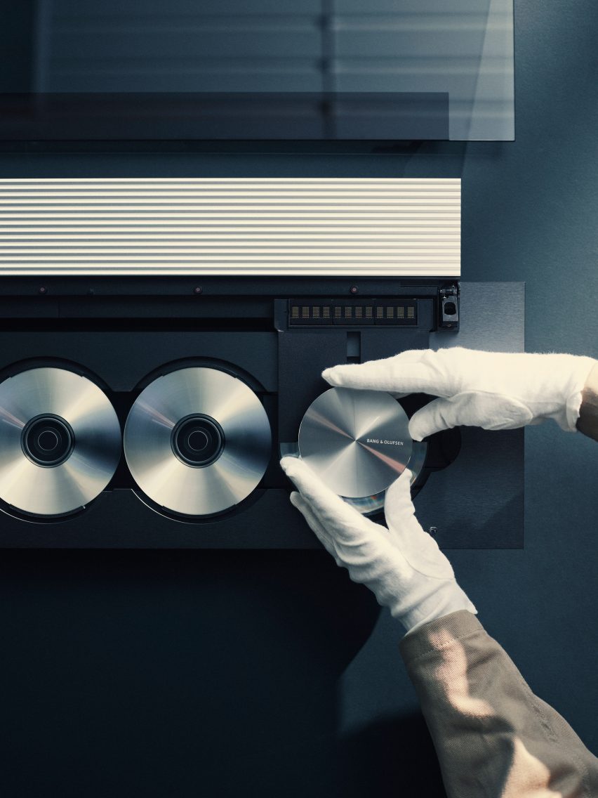 Overhead photo of white-gloved hands handling the components of a Beosound 9000 CD player as it is cleaned and restored