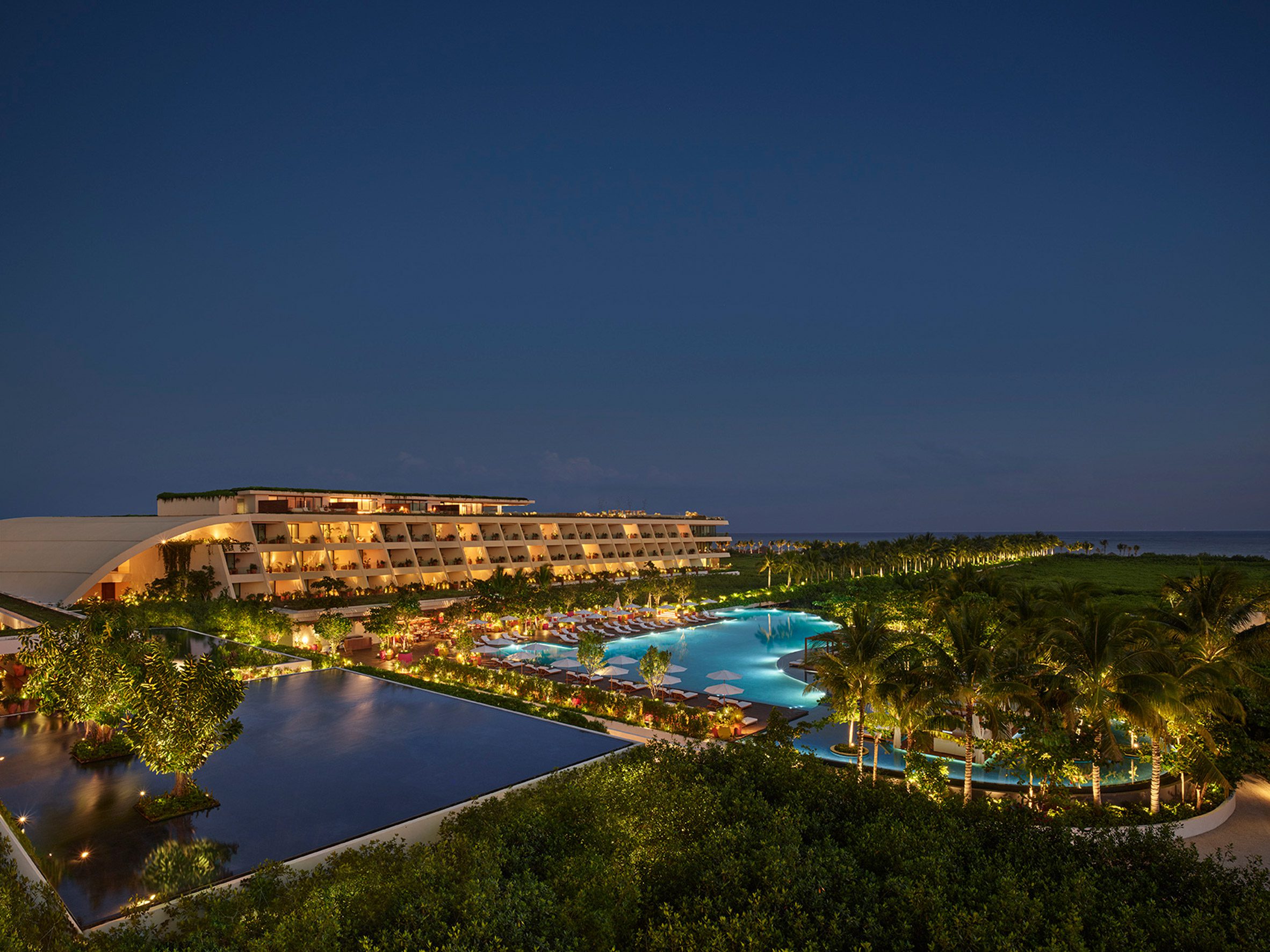 Night view of the pools and buildings of Riviera Maya Edition