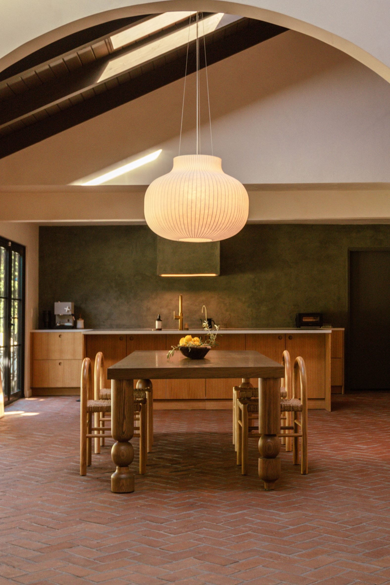Kitchen and dining room with mono-pitched ceiling and brick floor