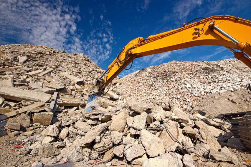 Construction and concrete demolition waste recycling site with excavator boom crusher