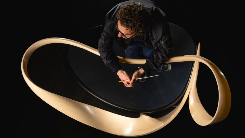 Conductor Teddy Abrams leaning on conductor's rail designed by Joseph Walsh Studio