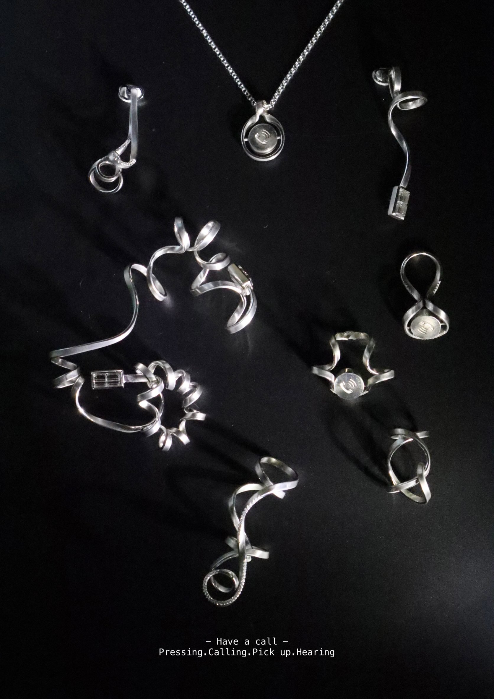 A photograph of silver jewellery pieces against a black background.