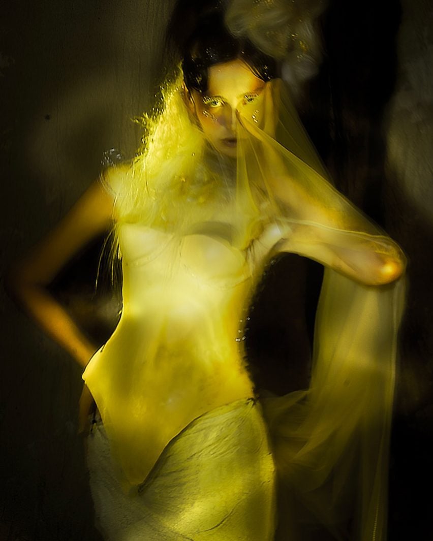 A blurred photograph of a person wearing yellow garments against a dark background.