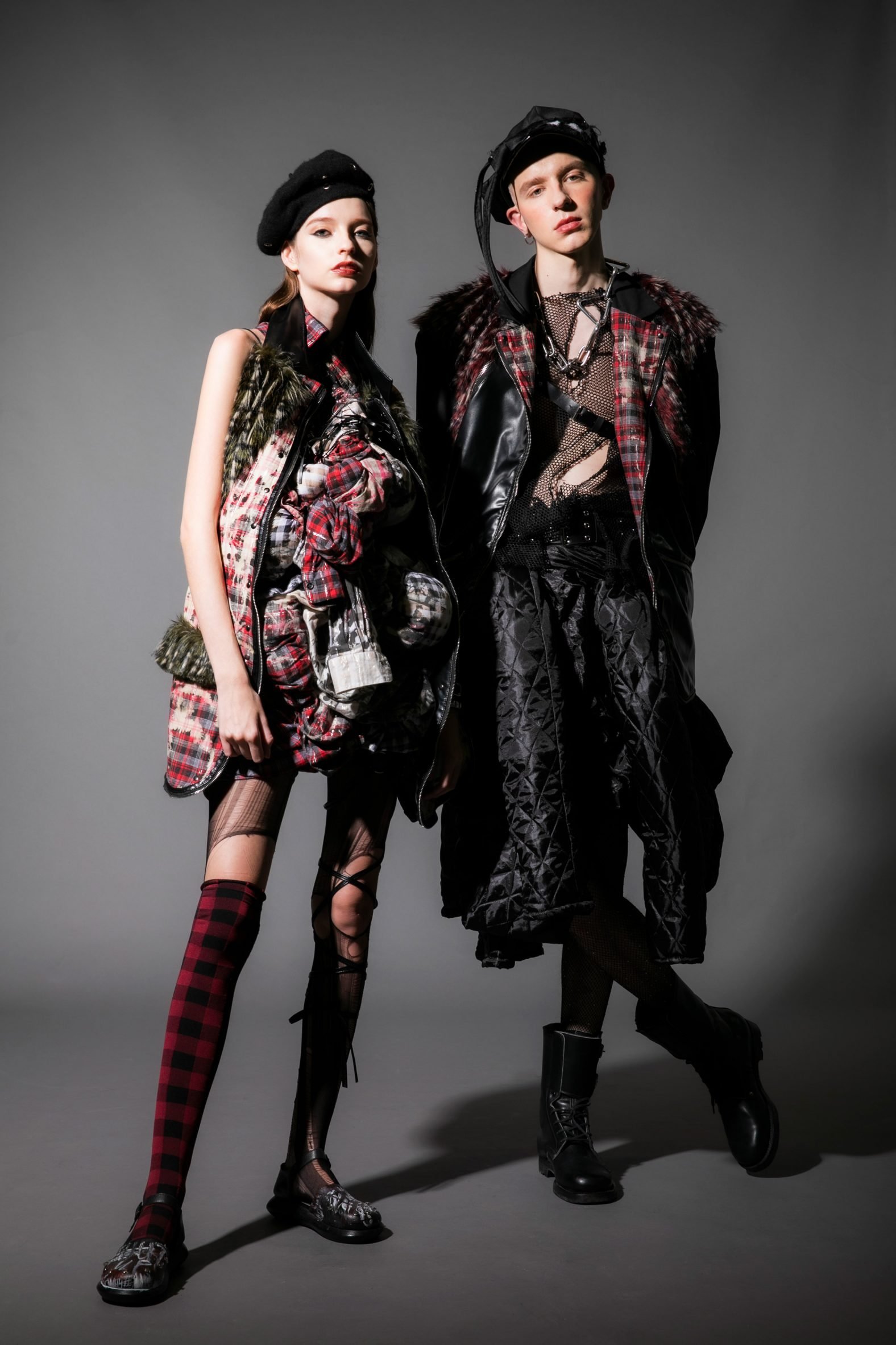 A photograph of two people wearing fashion designs in colours of black, red and green.