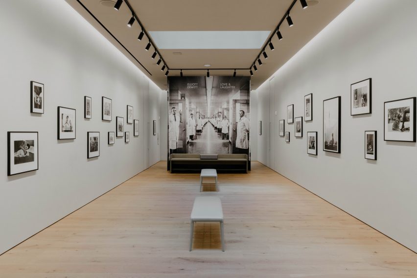 A photography gallery with white walls and pale wood flooring