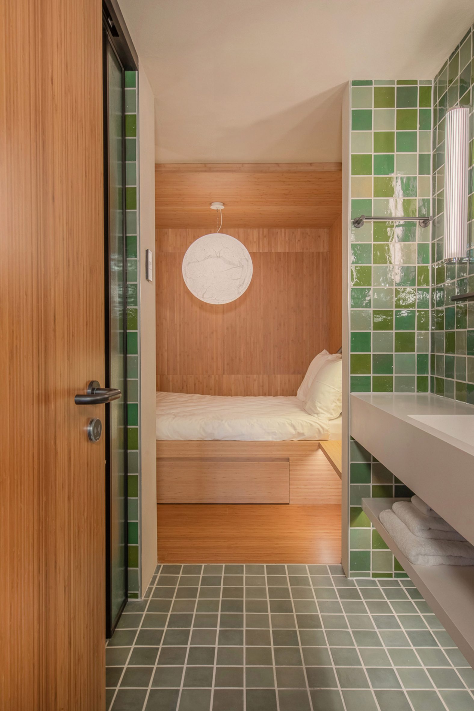 View from bathroom with green tiles into wood-lined bedroom 