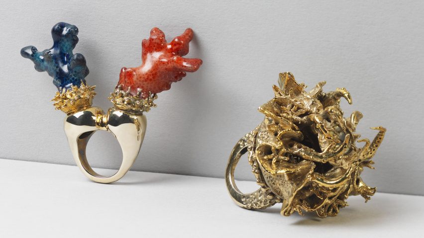 Two gold rings placed on a white surface, one with blue and red embellishing and another with gold embellishing.