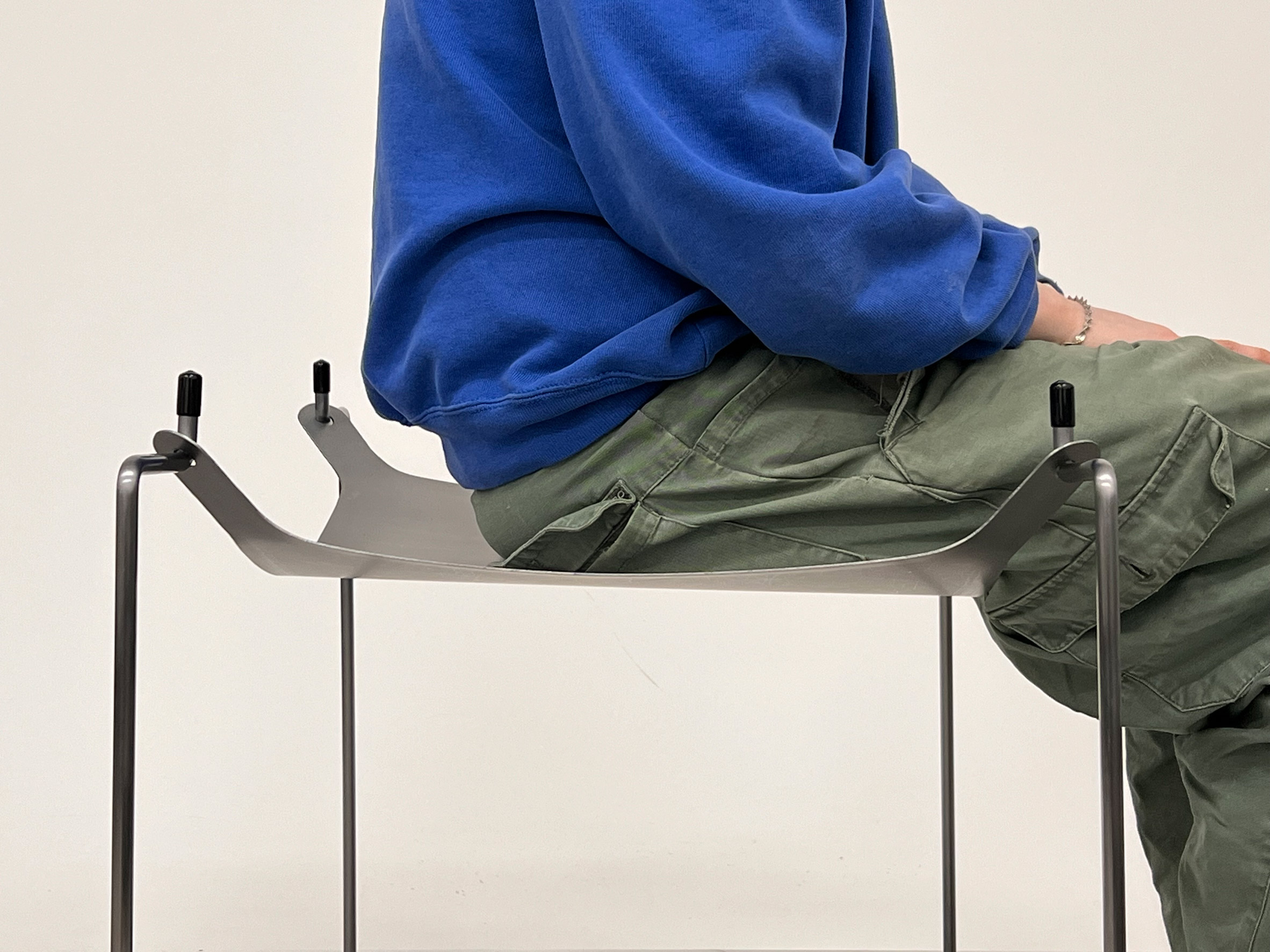 A person sitting on a metal stool.