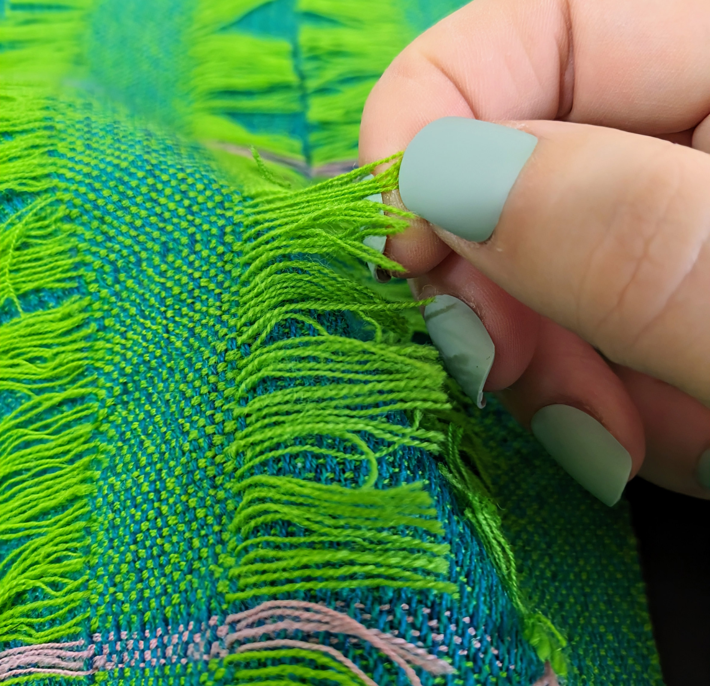 A photograph of a person handling a blue and green fabric.