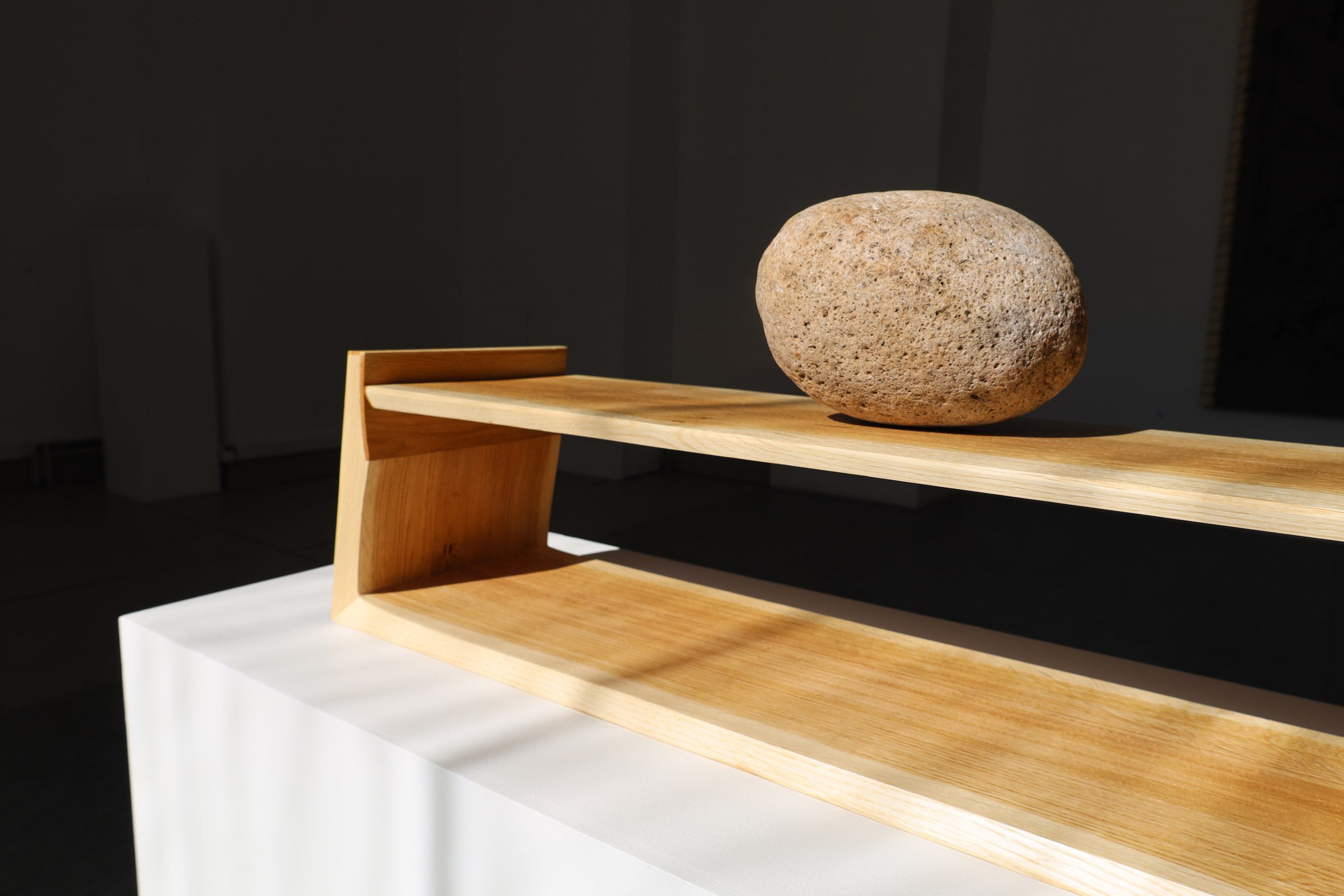 An image of a large brown stone on a brown wooden plinth.