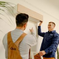 Photo of two men installing a Quilt climate control system on the wall of a room