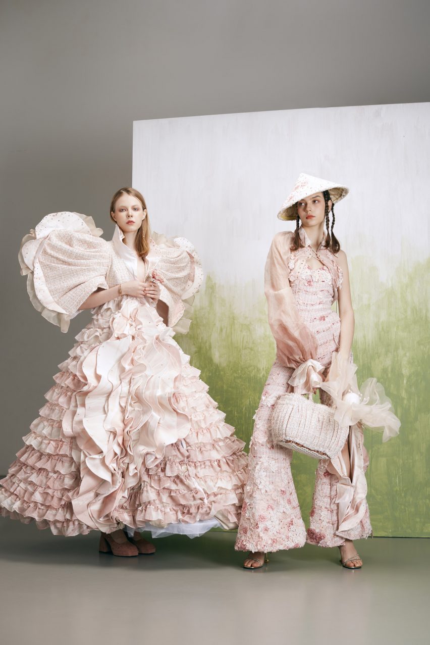 A photograph showing two models wearing pink garments on a grey, white and green backdrop.