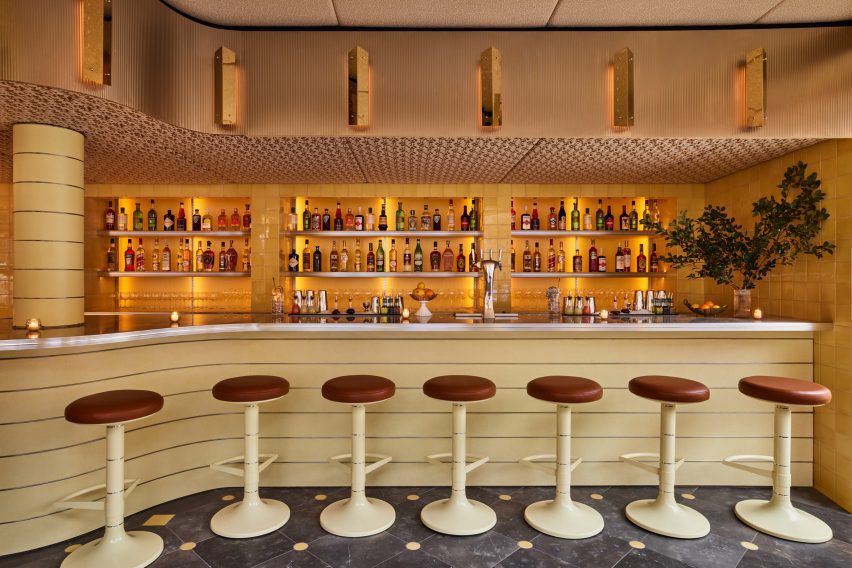 Bar with stainless steel ribbon above and seven stools in front