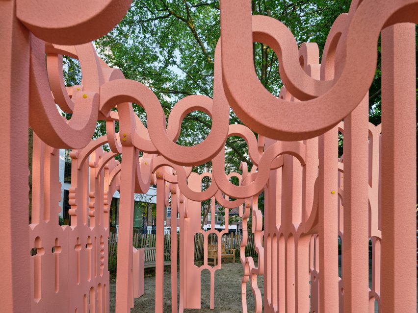 Pink arches of Impossible Possible Pavilion against background of trees 