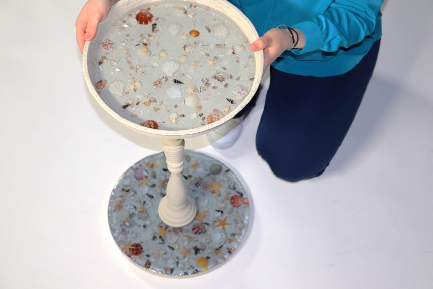 Person holding a side table with shells set in resin.