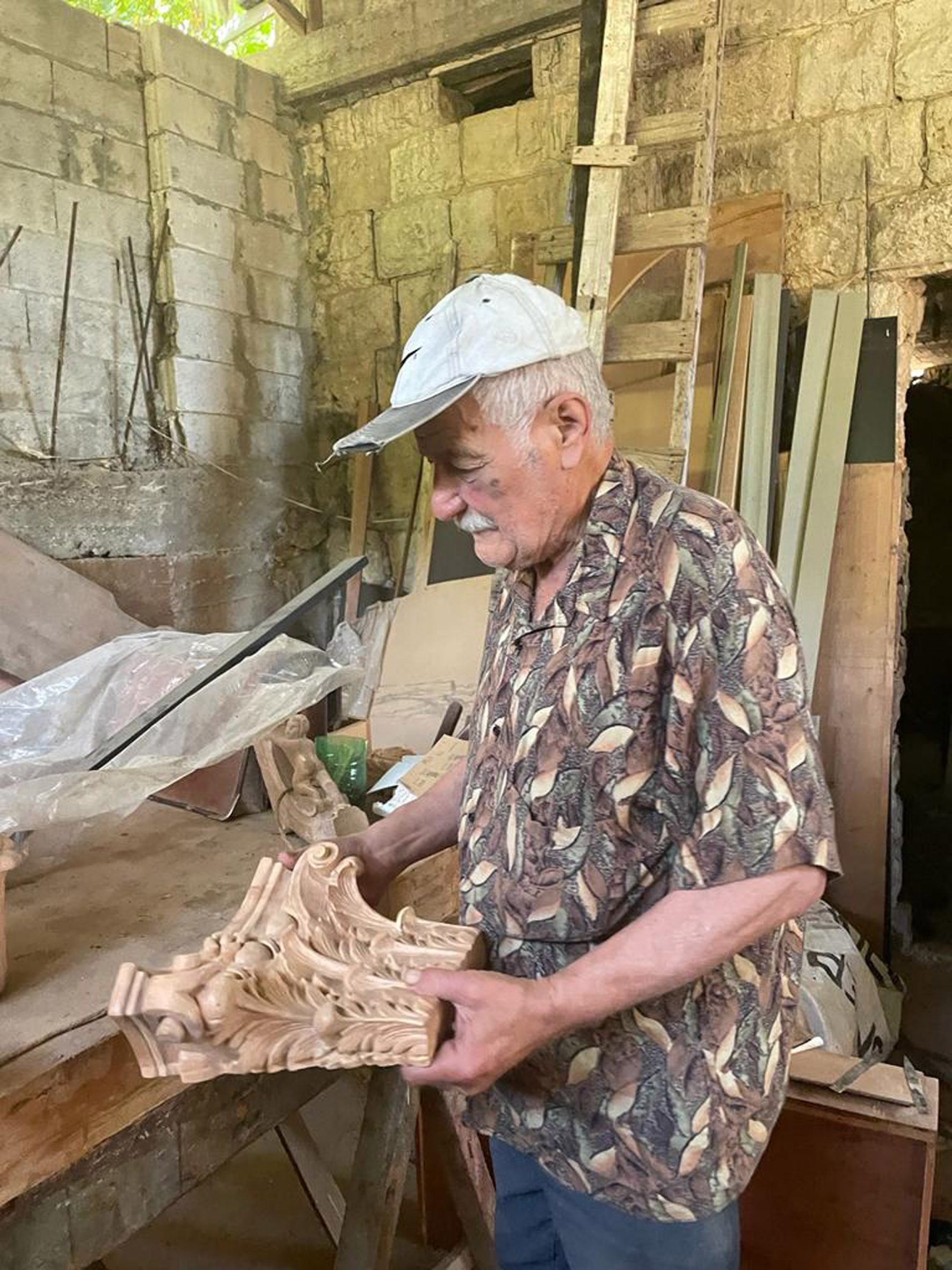 Photo of artisan Elie Ayrouth sculpting an ornate capital for the top of a column