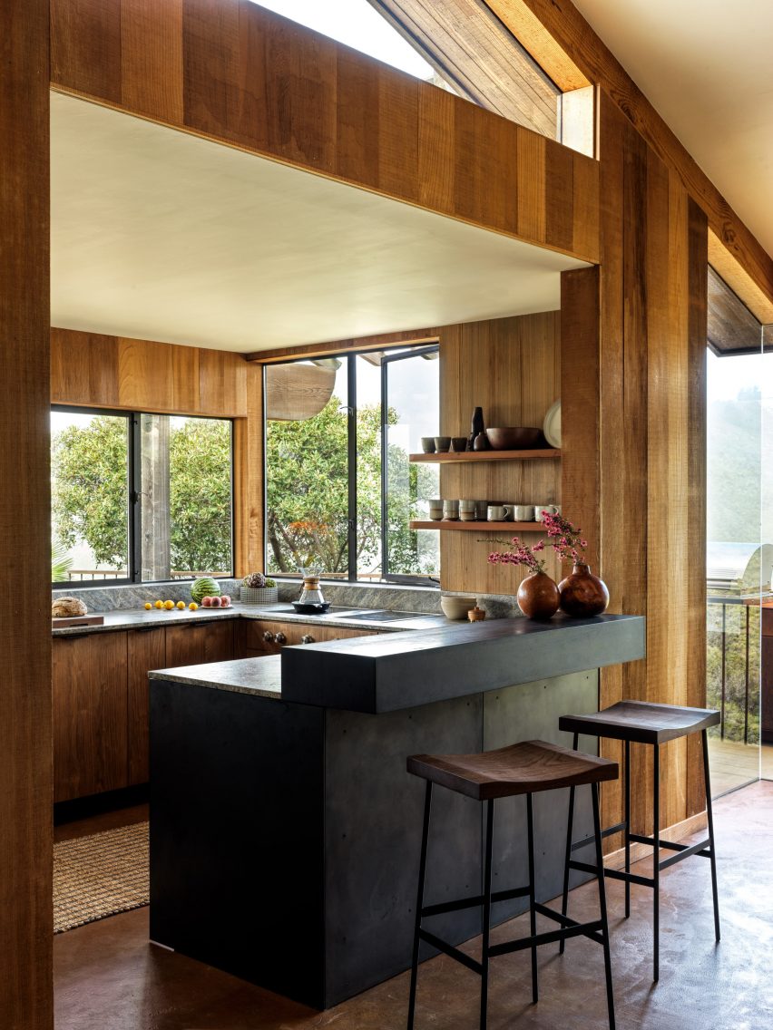 Compact kitchen with redwood panelling and raw steel breakfast bar