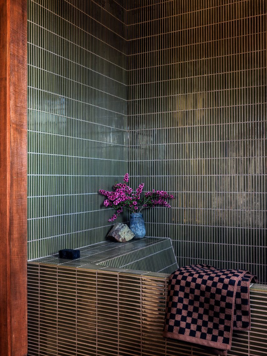 Bathroom tiled entirely in thin, straight-stacked teal glazed tiles
