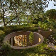 Cylindrical voids accommodate trees at Mexican lake house by MCxA Group