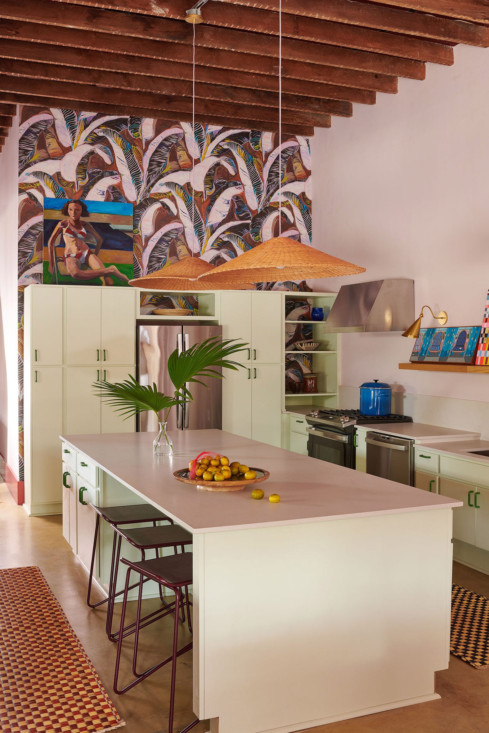 Kitchen with pale green cabinets and tropical wallpaper