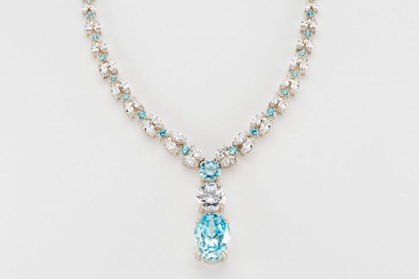 A photograph of a necklace against a white background, featuring silver and blue jewels.