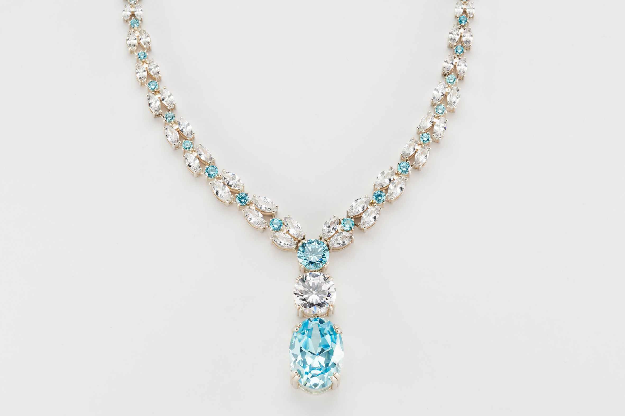 A photograph of a necklace against a white background, featuring silver and blue jewels.