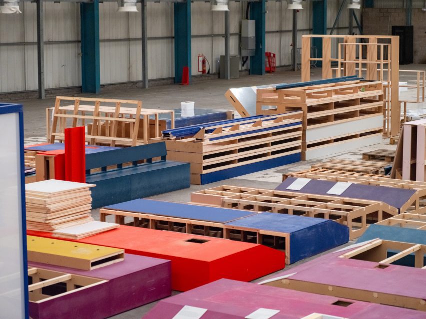 Photo of colourful stacks of painted wooden frames and panels that were formerly exhibition materials held within a large warehouse