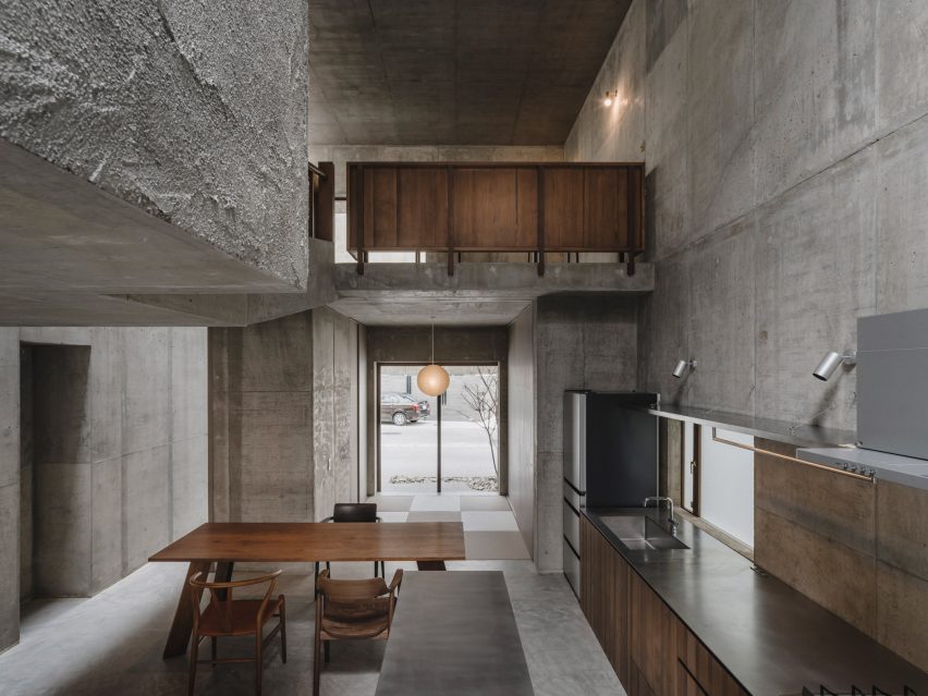 Kitchen and dining space within concrete home by Studio Cochi Architects