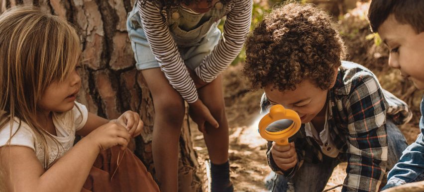 A photograph of children in outdoors, one holding an orange-coloured device.