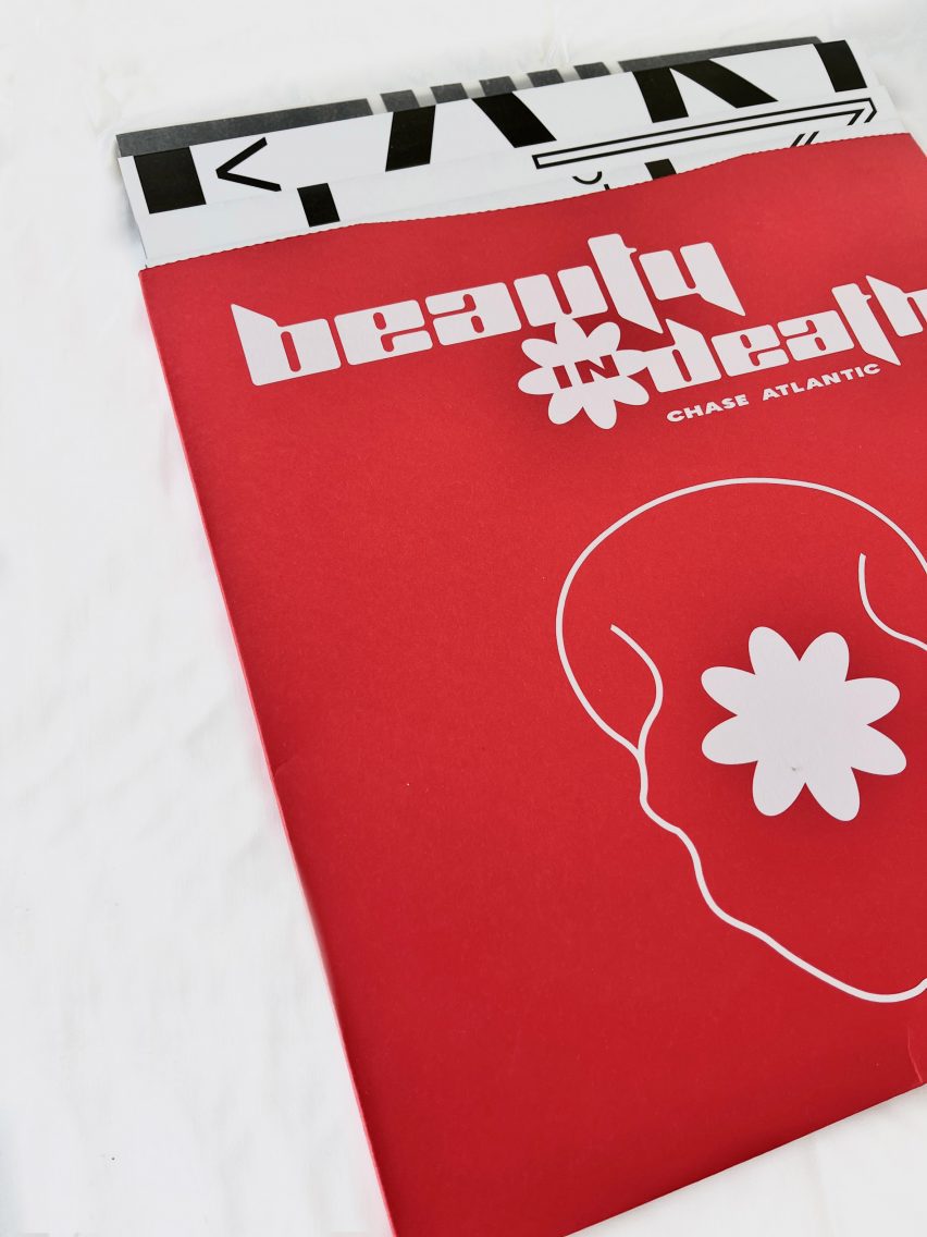A close up image of a publication with a red cover, with a white abstract illustration on the front and the words 'beauty in death', 'chase atlantic' written in white above it.