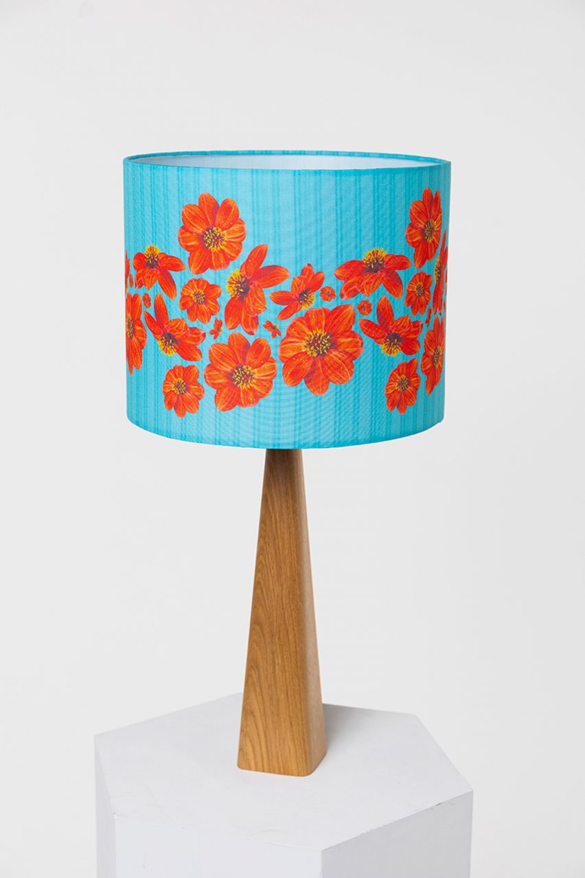 A photograph of a brown wooden lamp, with a blue and red floral lampshade, against a white backdrop.