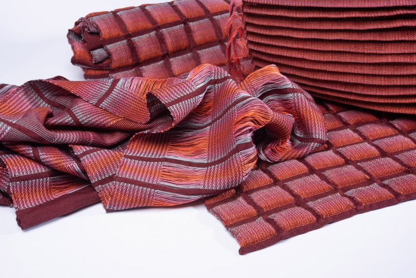 A photograph of a piece of fabric in tones of red, blue and orange with a grid pattern on it.