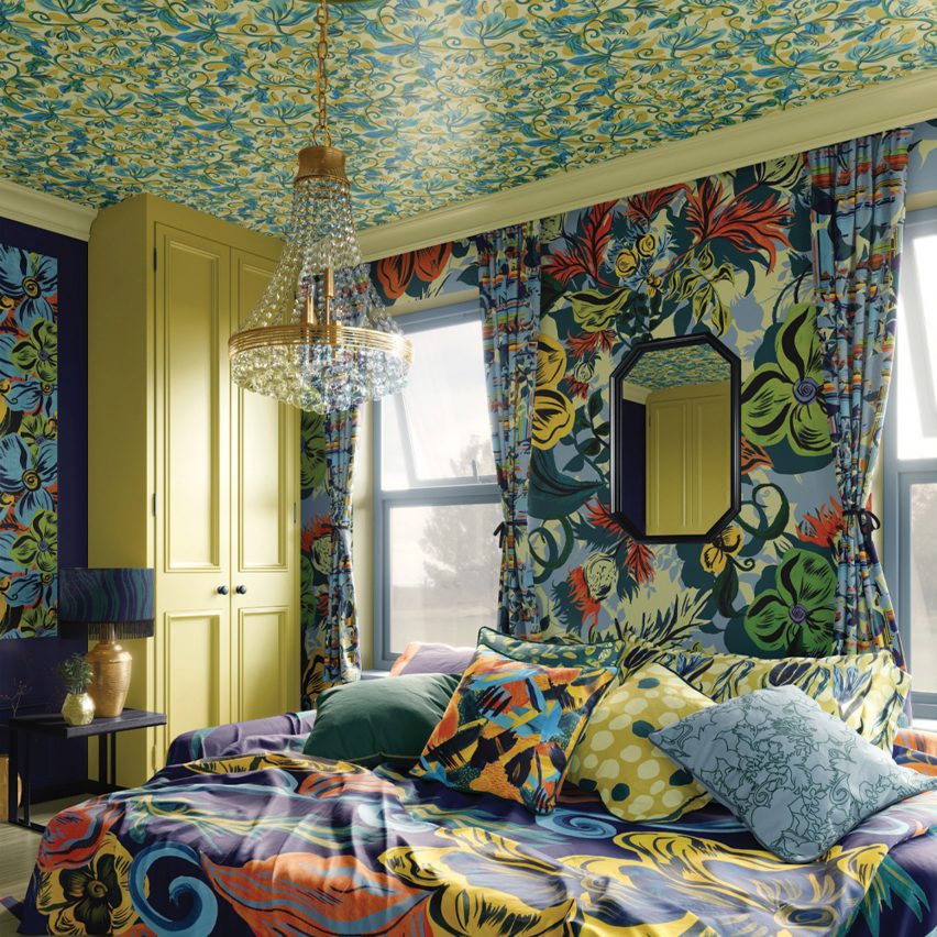 A photograph of a bedroom with floral patterns on the walls and ceilings, and on the bedding, all in colours of blue, green, yellow and red.