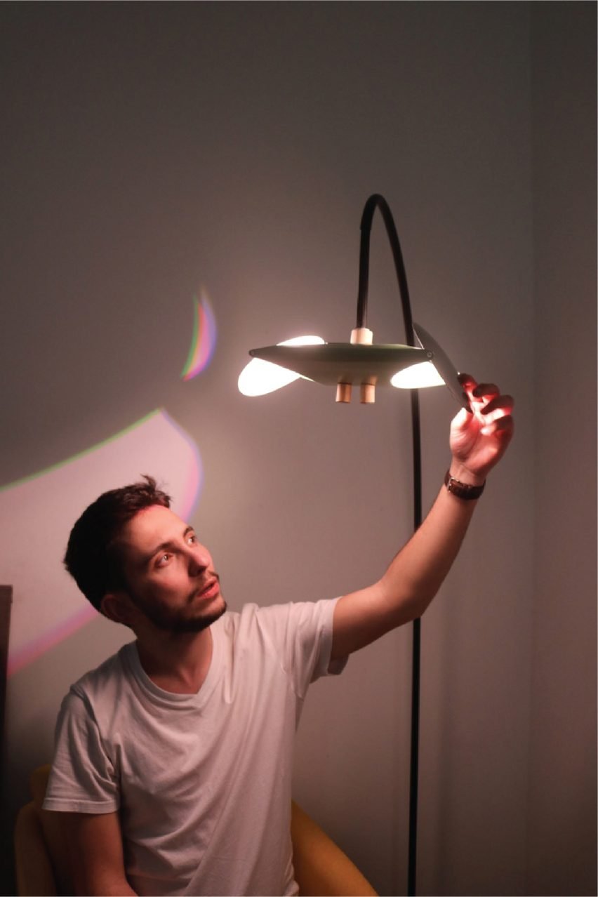 A photograph of a person handling an illuminated lamp against a grey backdrop.