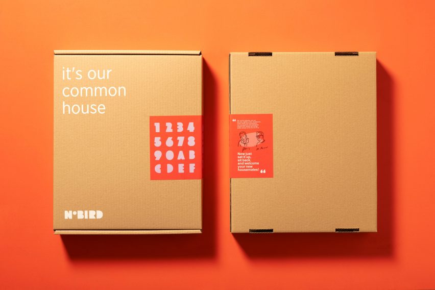 A photograph of two closed cardboard boxes next to one another against an orange background. One on the left has the words 'it's our common house' written on them in white writing.