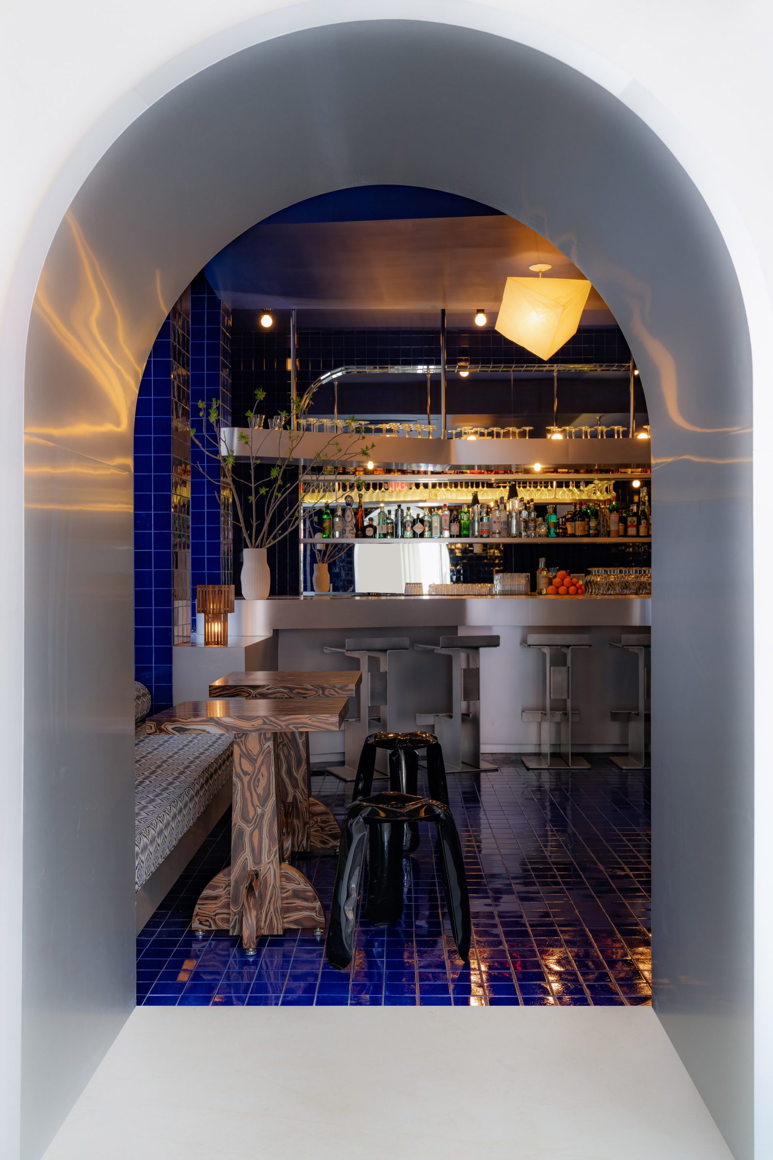 Arched opening leading into a bar area lined with cobalt blue tiles