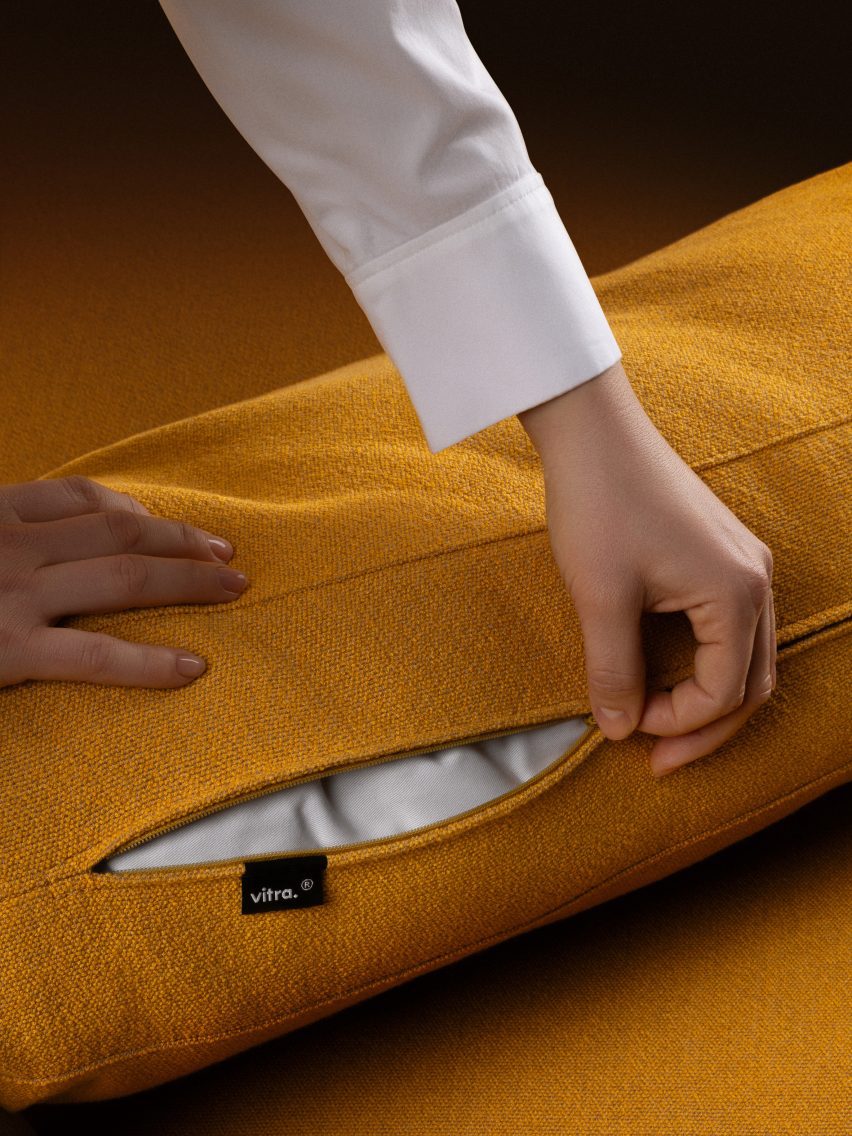 Photo of a person unzipping the cover of a golden yellow Vitra sofa cushion