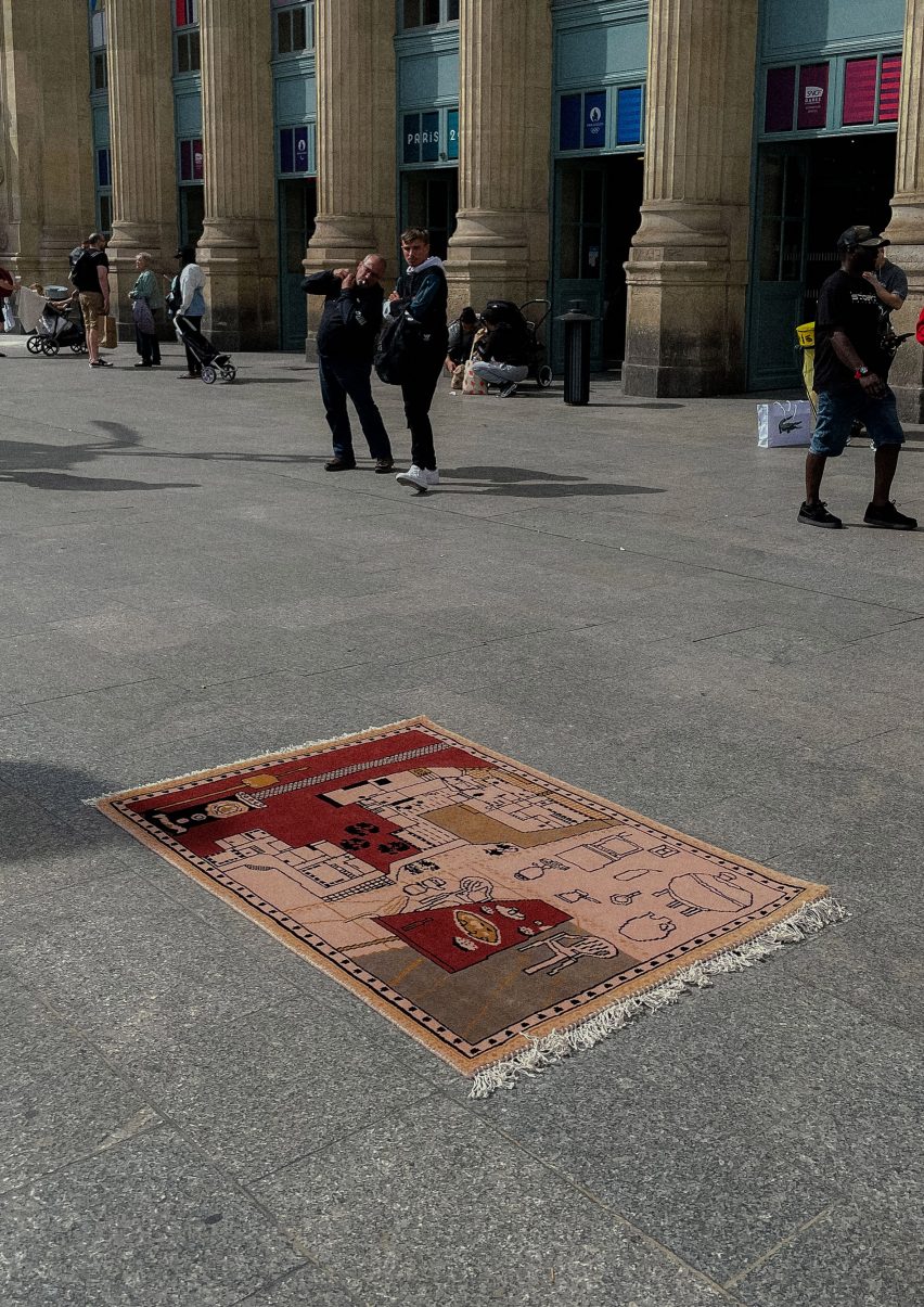 A photograph of a pink and red rug on the ground in a public space.