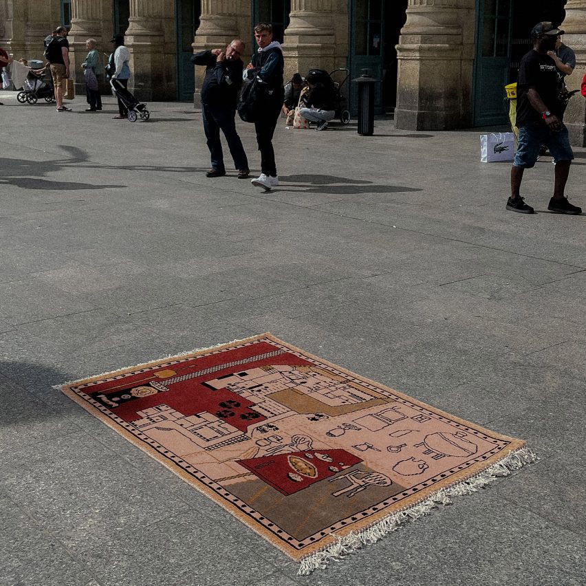 A photograph of a pink and red rug on the ground in a public space.