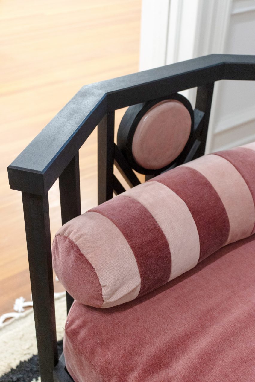 A photograph of the edge of a piece of furniture with pink cushions on it.