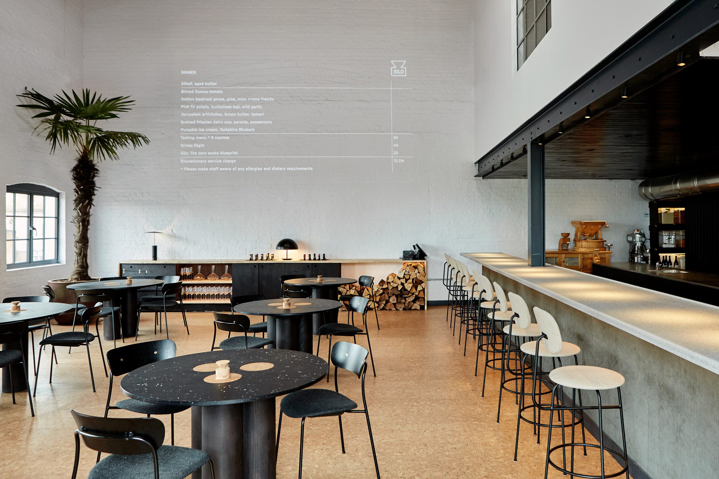 Double-height restaurant interior with menu projected onto the wall